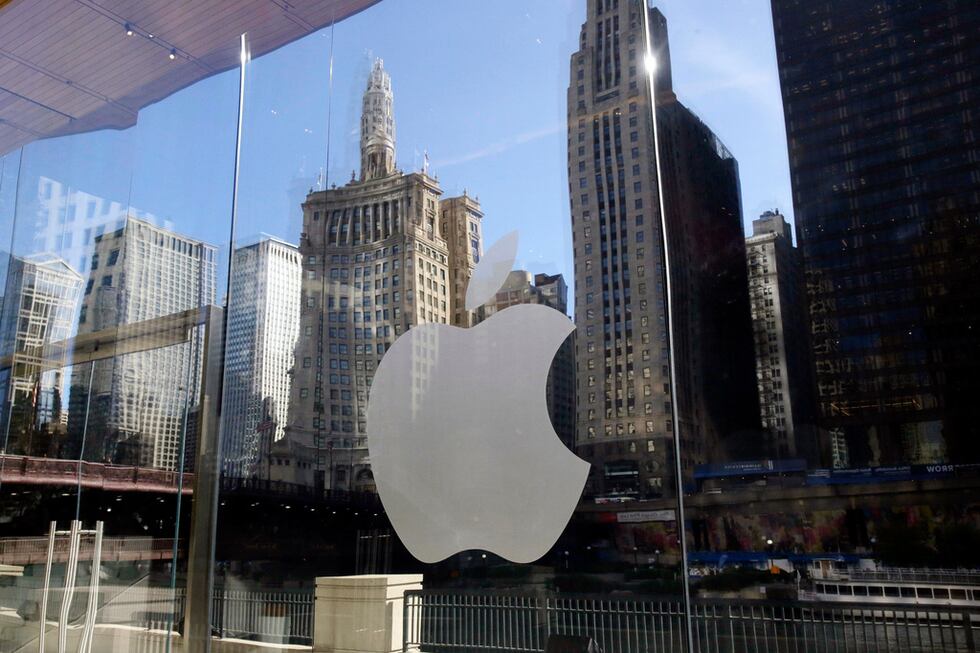ARCHIVO - Edificios se reflejan detrás del logo de una tienda de Apple, en el centro de...