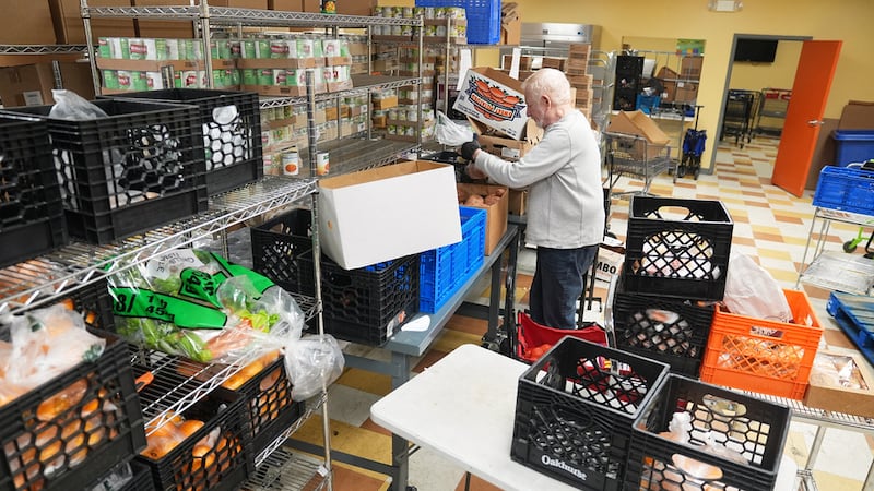 El voluntario Bruce Toben empaca comestibles durante un reparto de alimentos de emergencia del...